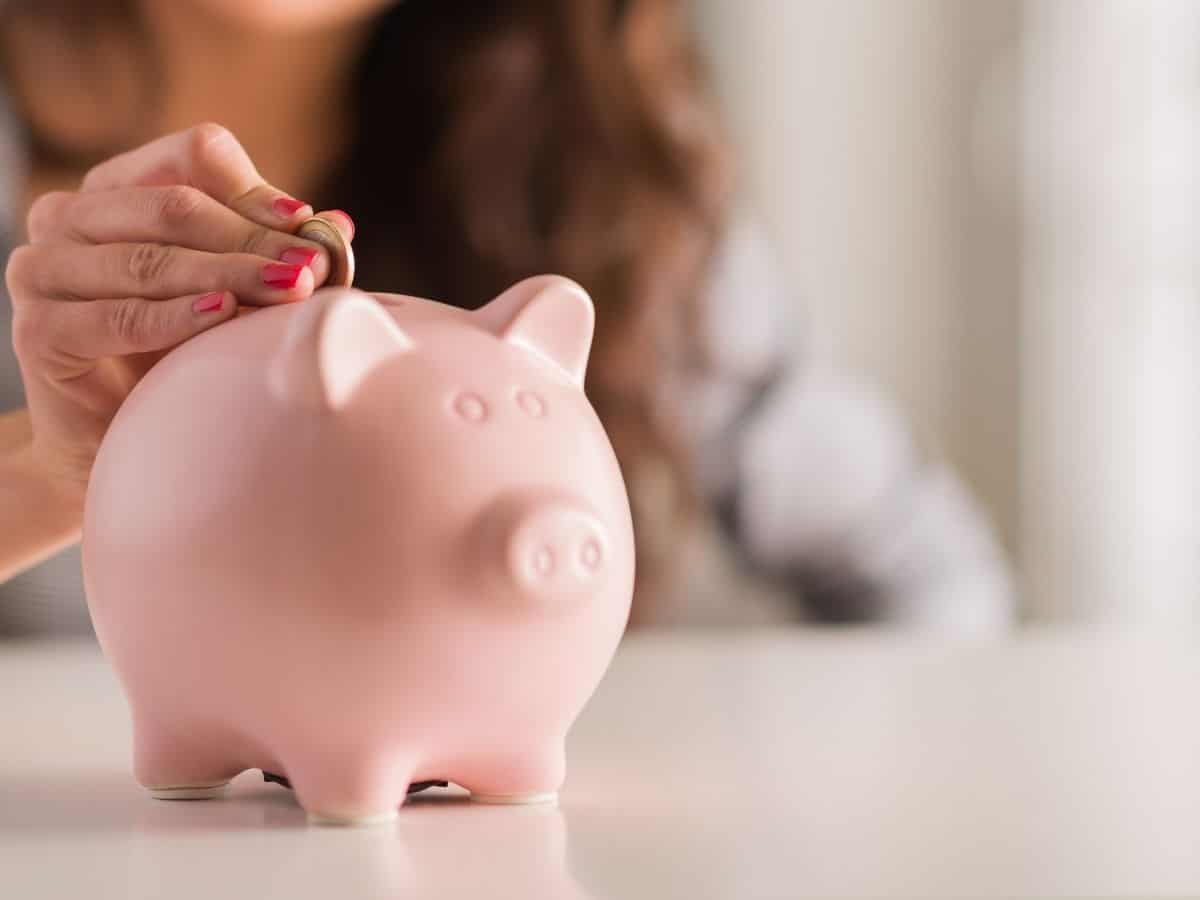 a woman putting coins in a piggy bank