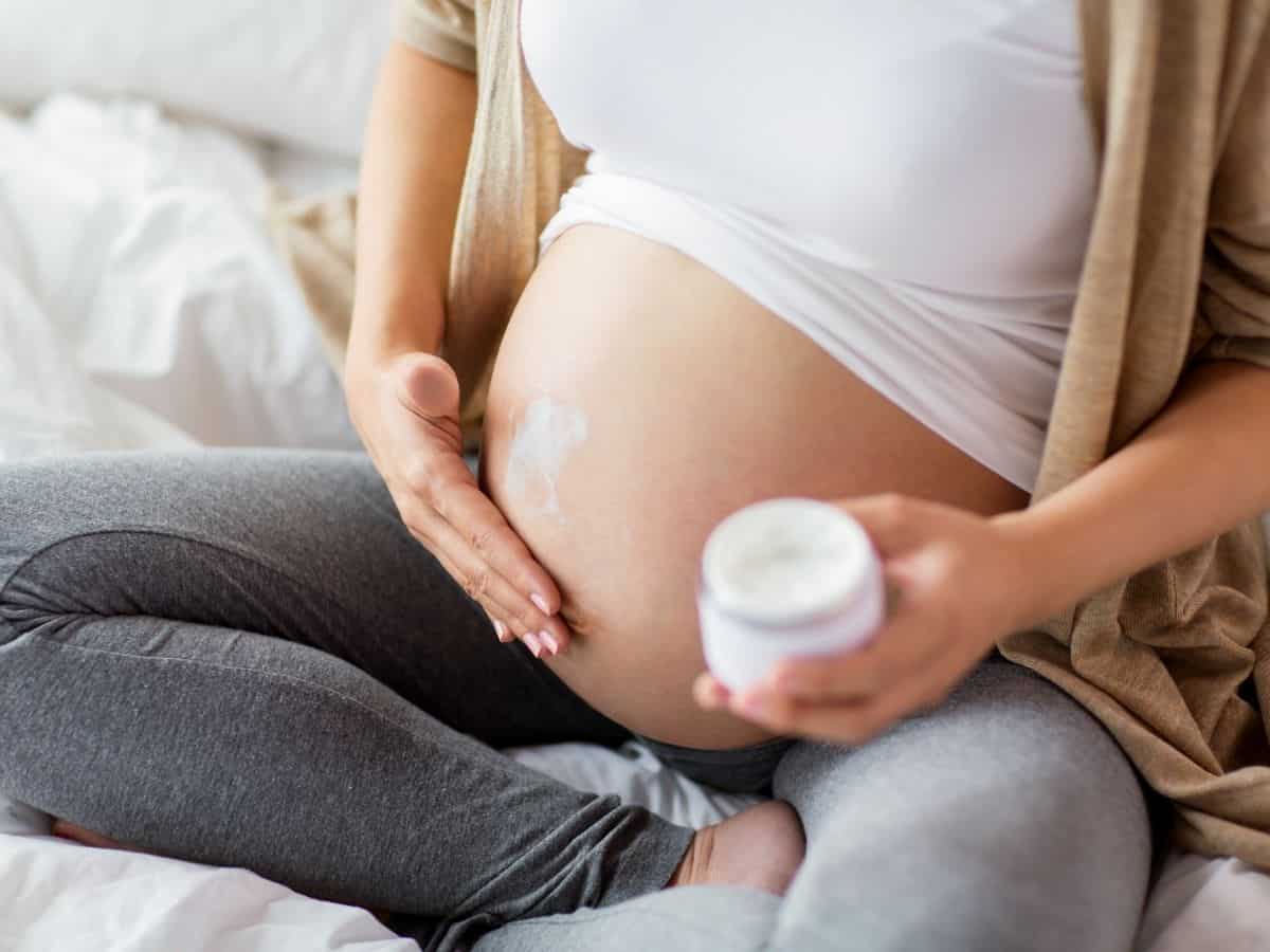 a pregnant woman applying a moisture cream to her belly.