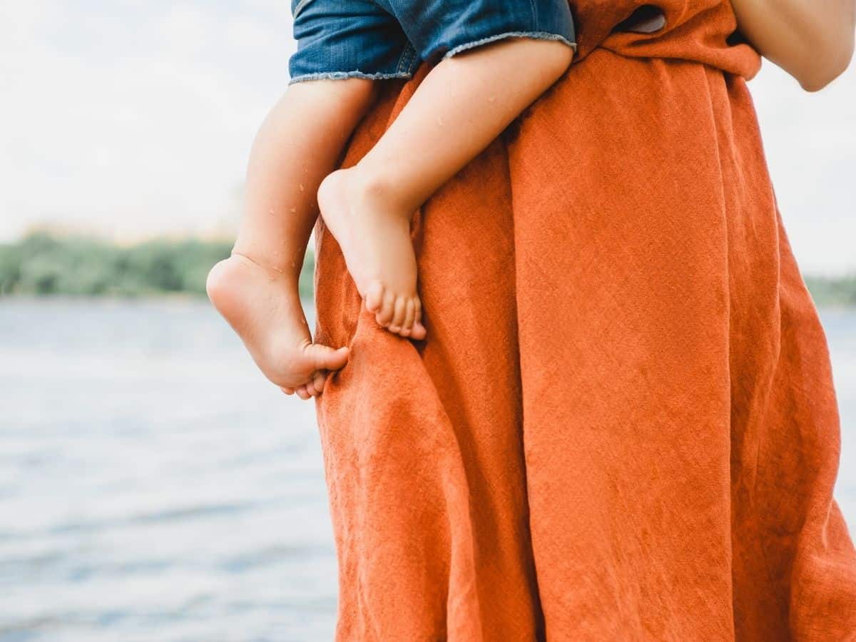 a mom in a dress holding her young child