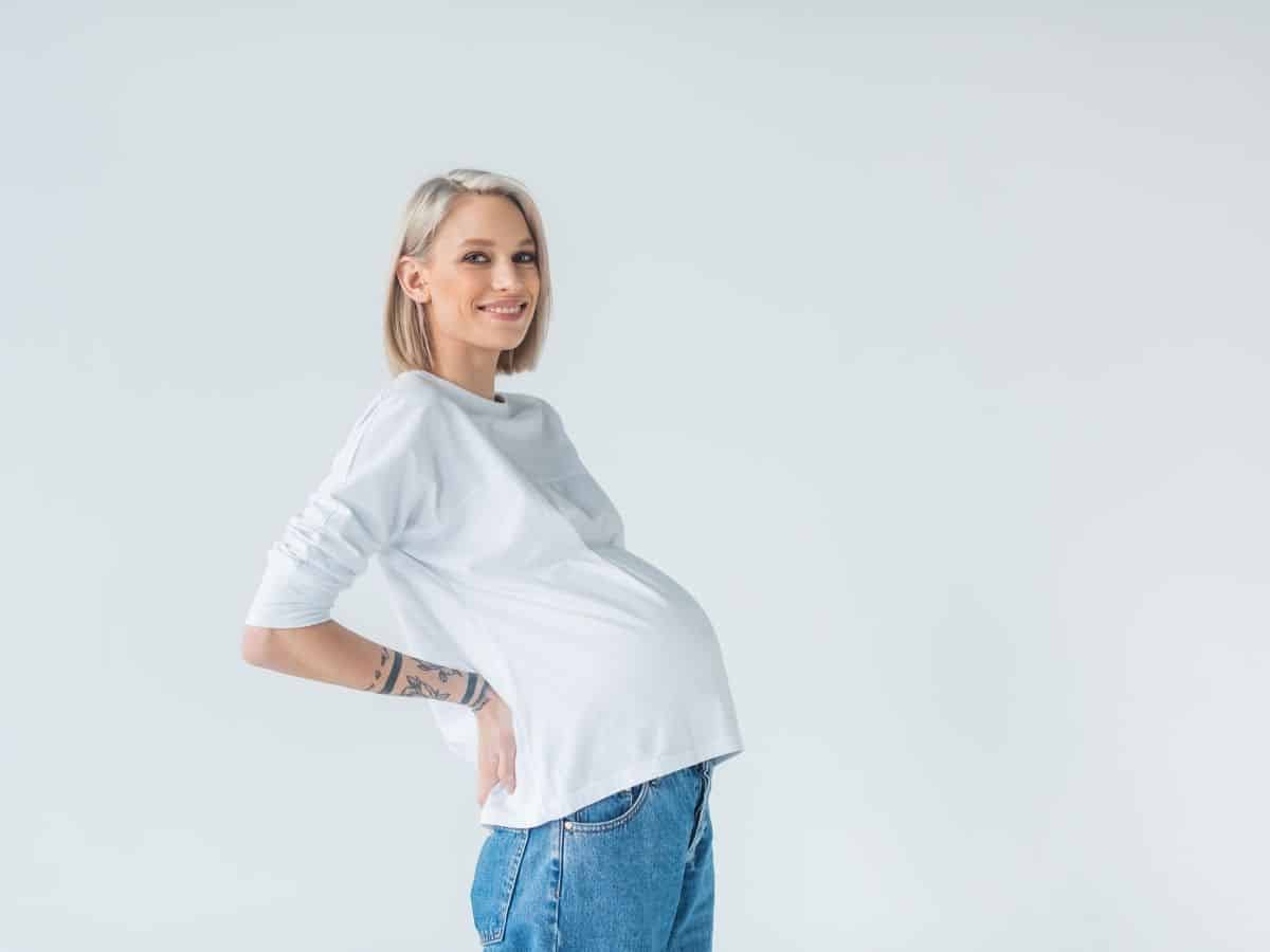 a pregnant woman wearing blue maternity jeans