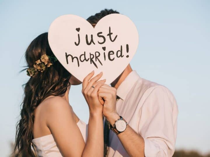newlyweds holding a heart shaped sign that says just married