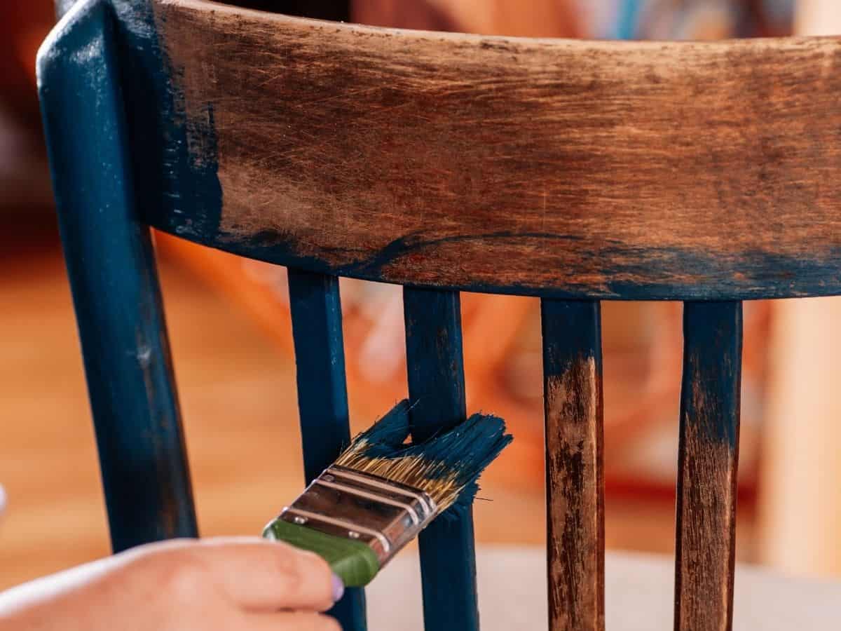 painting an old chair with a dark blue paint