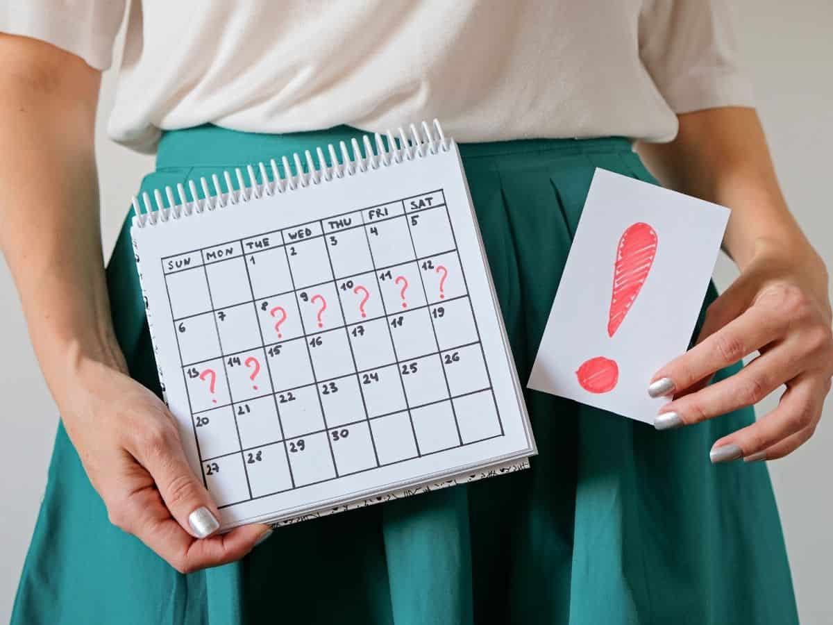 a woman holding up a schedule with question marks for a week