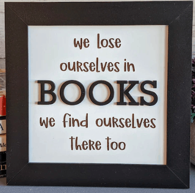 a framed artwork that says we lose ourselves in books we find ourselves there too.