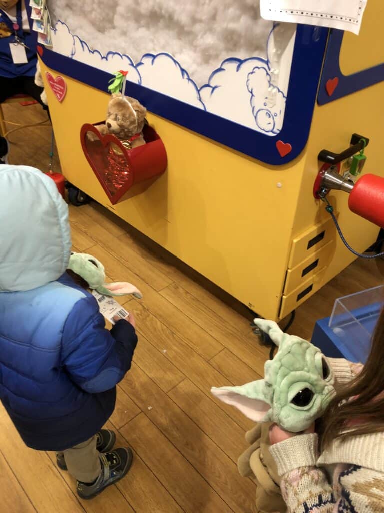 two kids with baby yoda plushes at build a bear