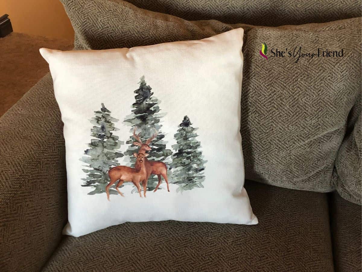 a throw pillow with winter trees and deer