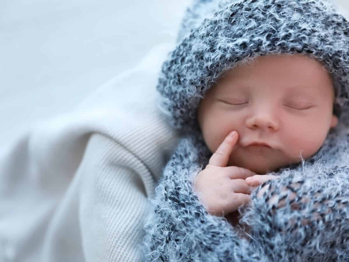 a baby wrapped in a gray wool hat and blanket