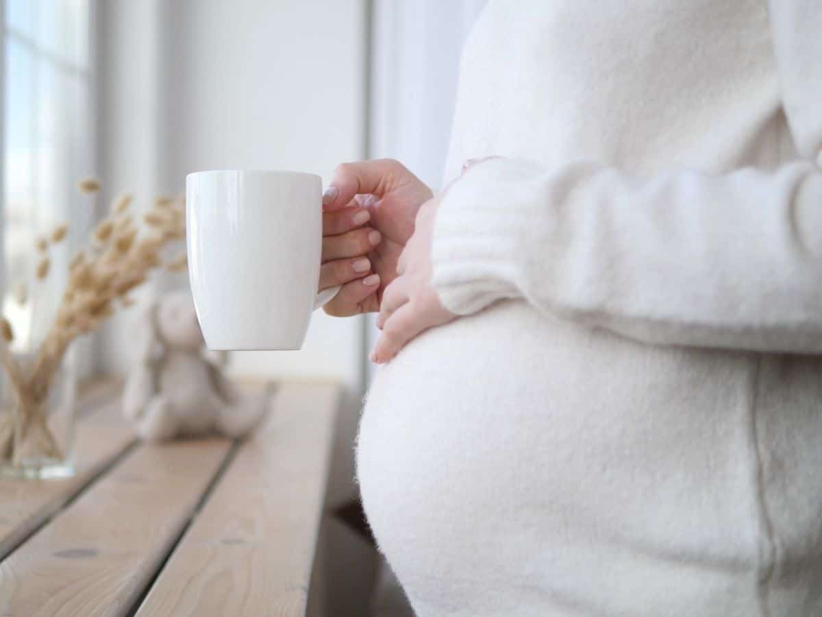 a pregnant woman holding a cup of tea