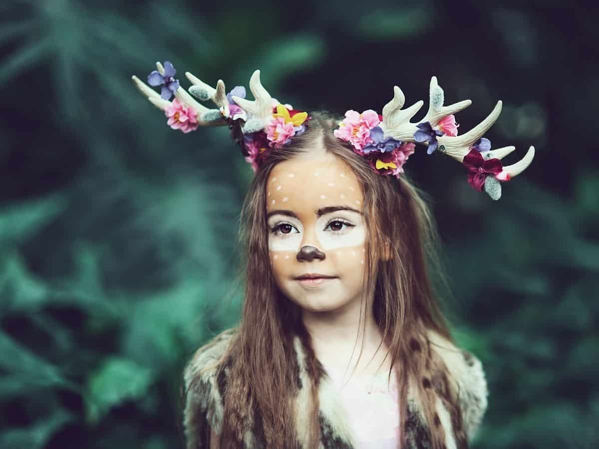 a young girl dressed in a mystical deer antlers and makeup