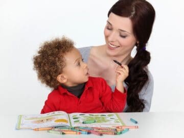 a mom and son coloring in a coloring book with crayons