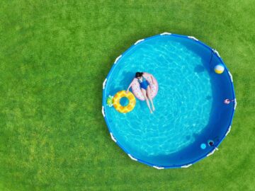 a woman sitting on an floatation device in a steel framed pool