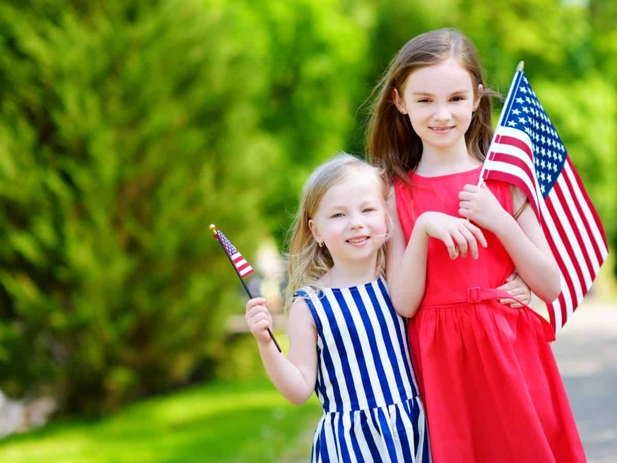 two girls wearing read and blue and white stripes holding american flags