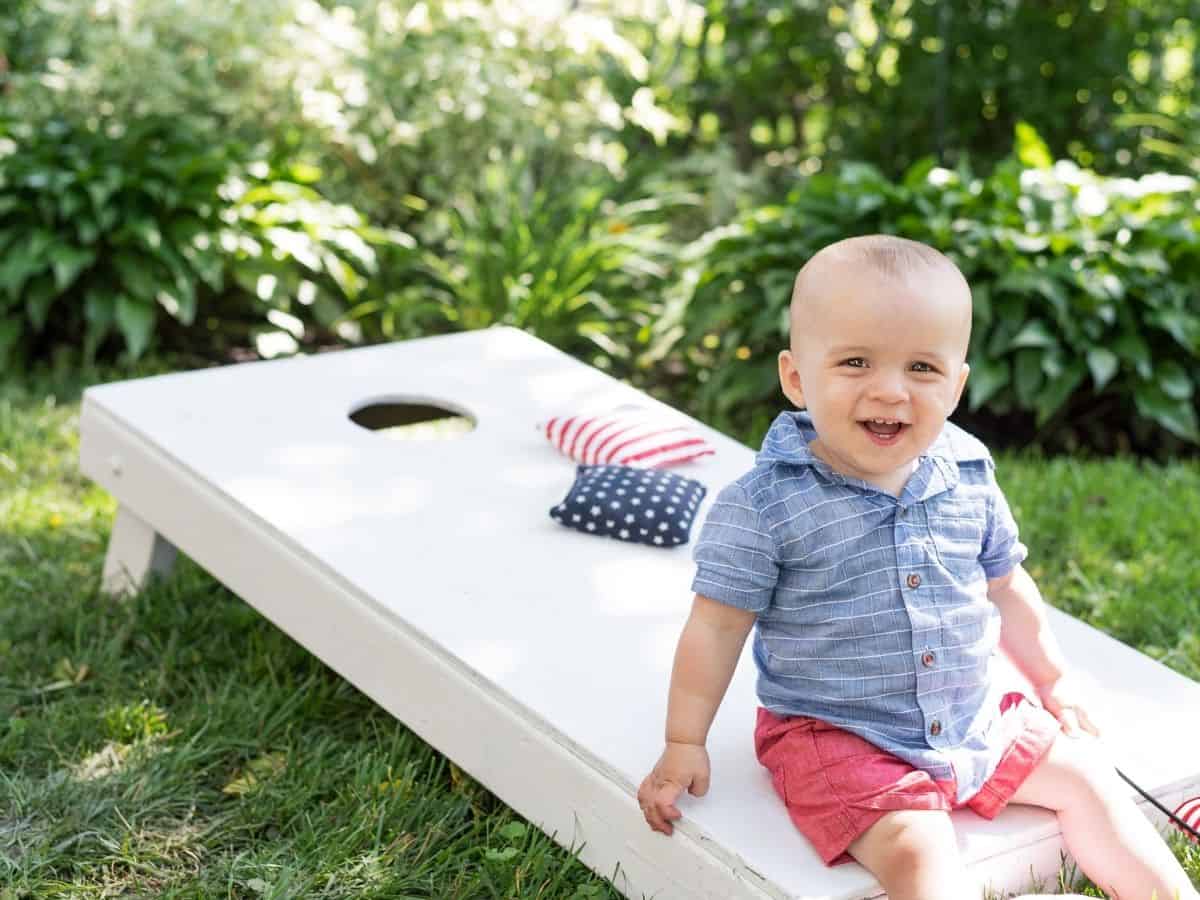 a child sitting on a corn hole game