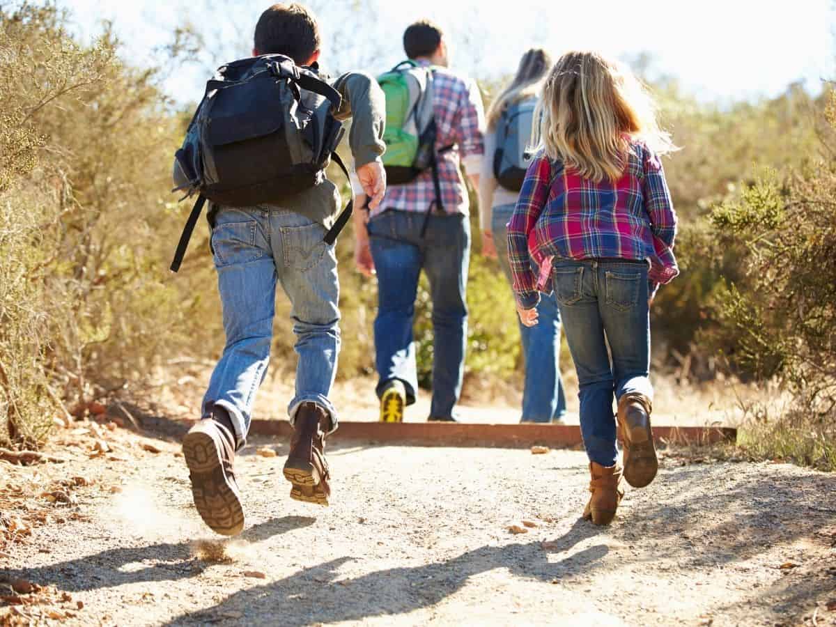 a mom dad and two kids hiking on a nature trail