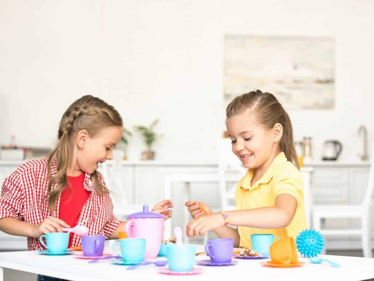 two little girls playing with a pretend tea set