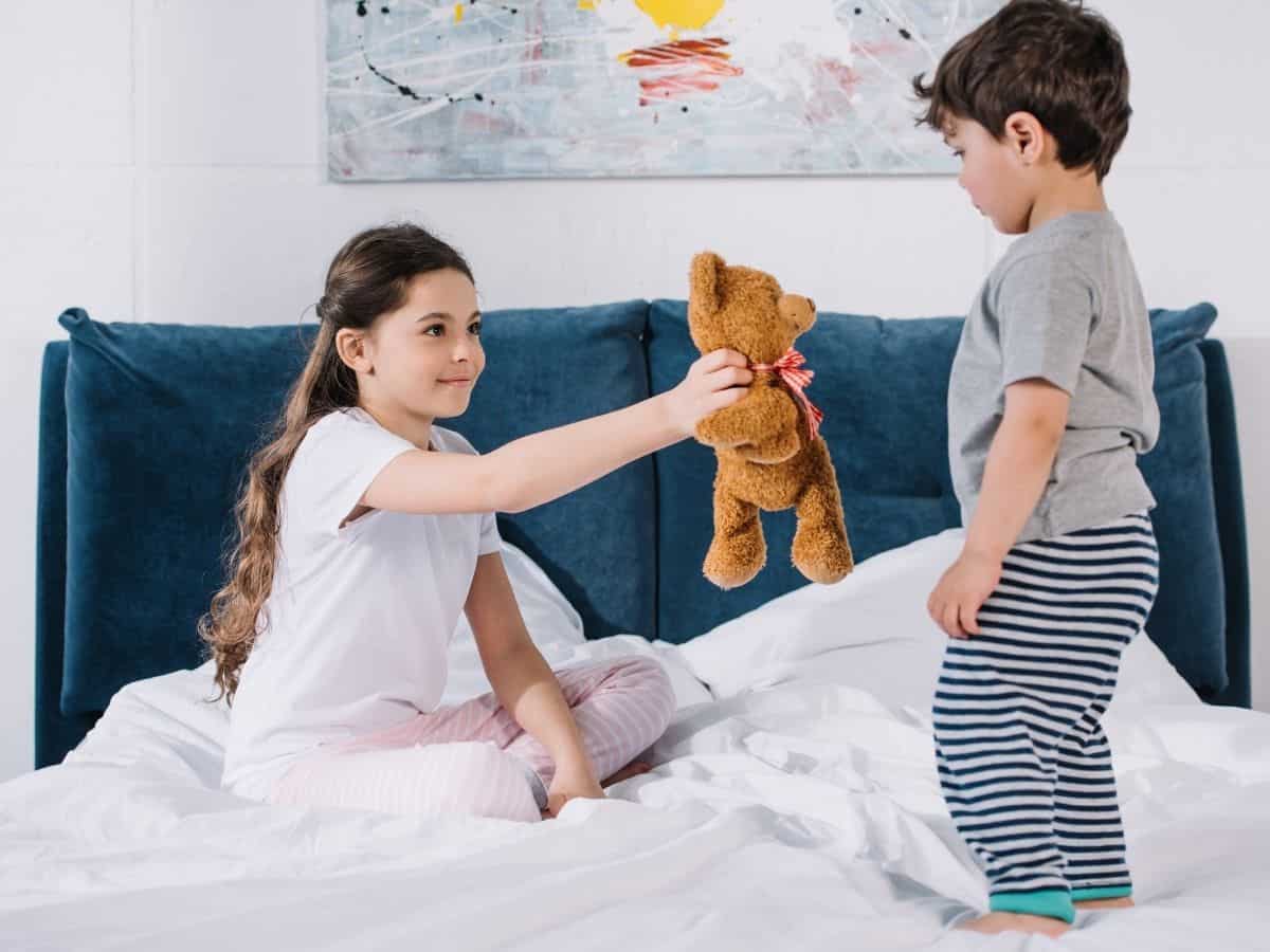 two kids playing on top of a bed