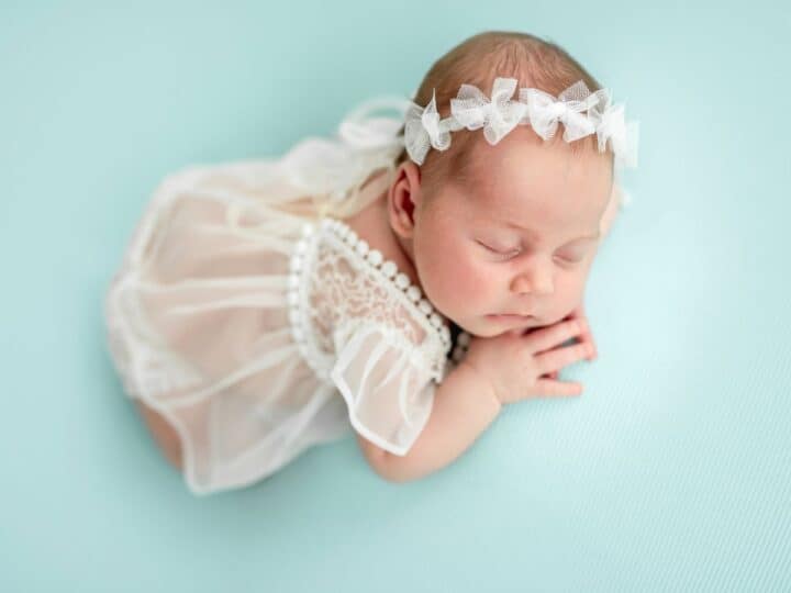 a baby girl in a white dress and head band