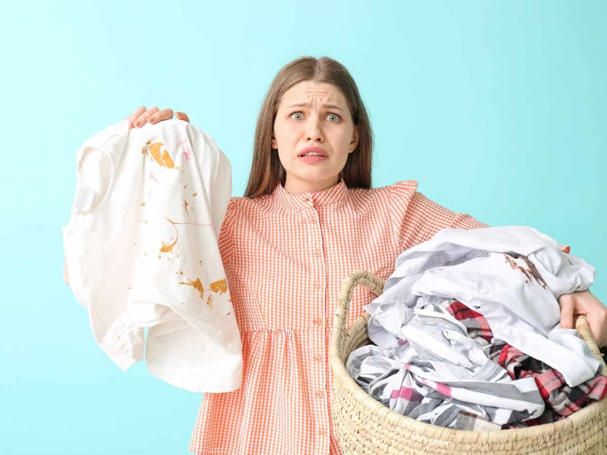 a woman doing laundry and holding up some stained clothes