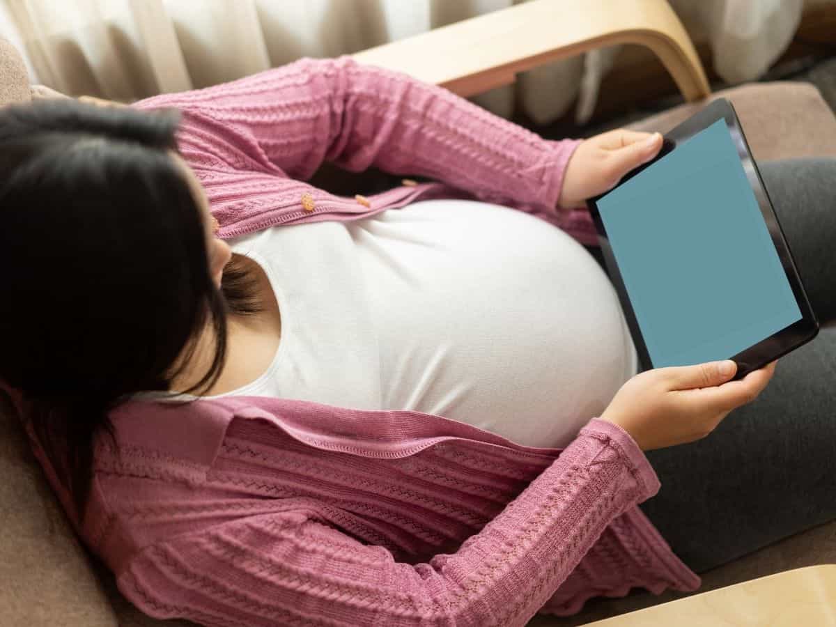 a pregnant woman holding her tablet.