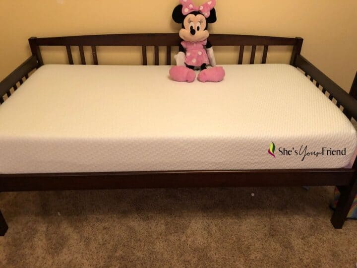 a mattress on a wooden bed frame with a kids stuffed animal Minnie mouse on it too