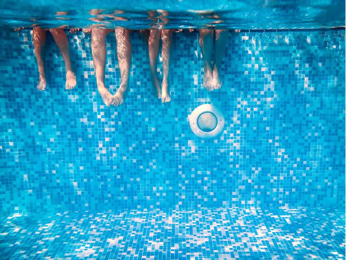 a family of four people's legs in the water of a pool