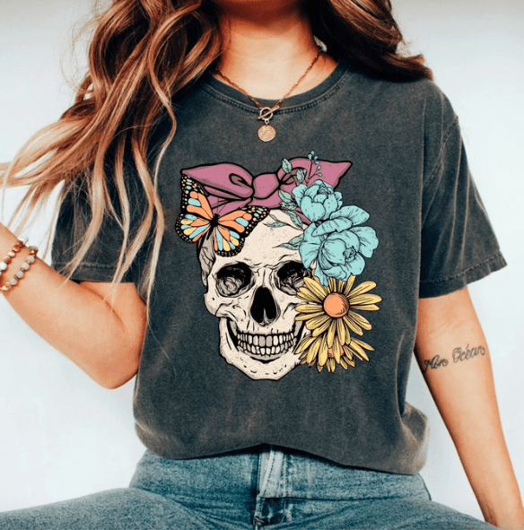 a woman wearing a shirt with a skull and flowers on it