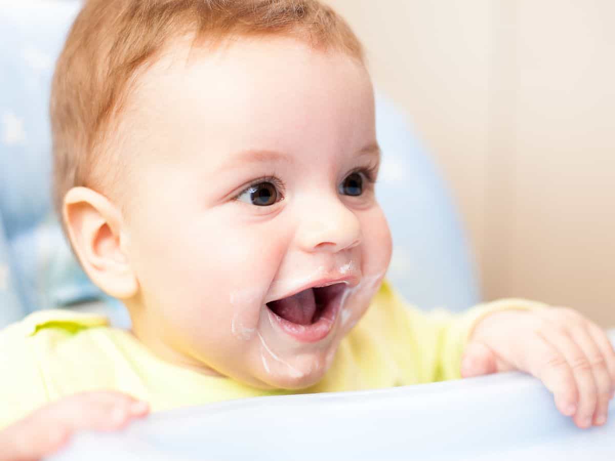 a baby in a high chair eating yogurt