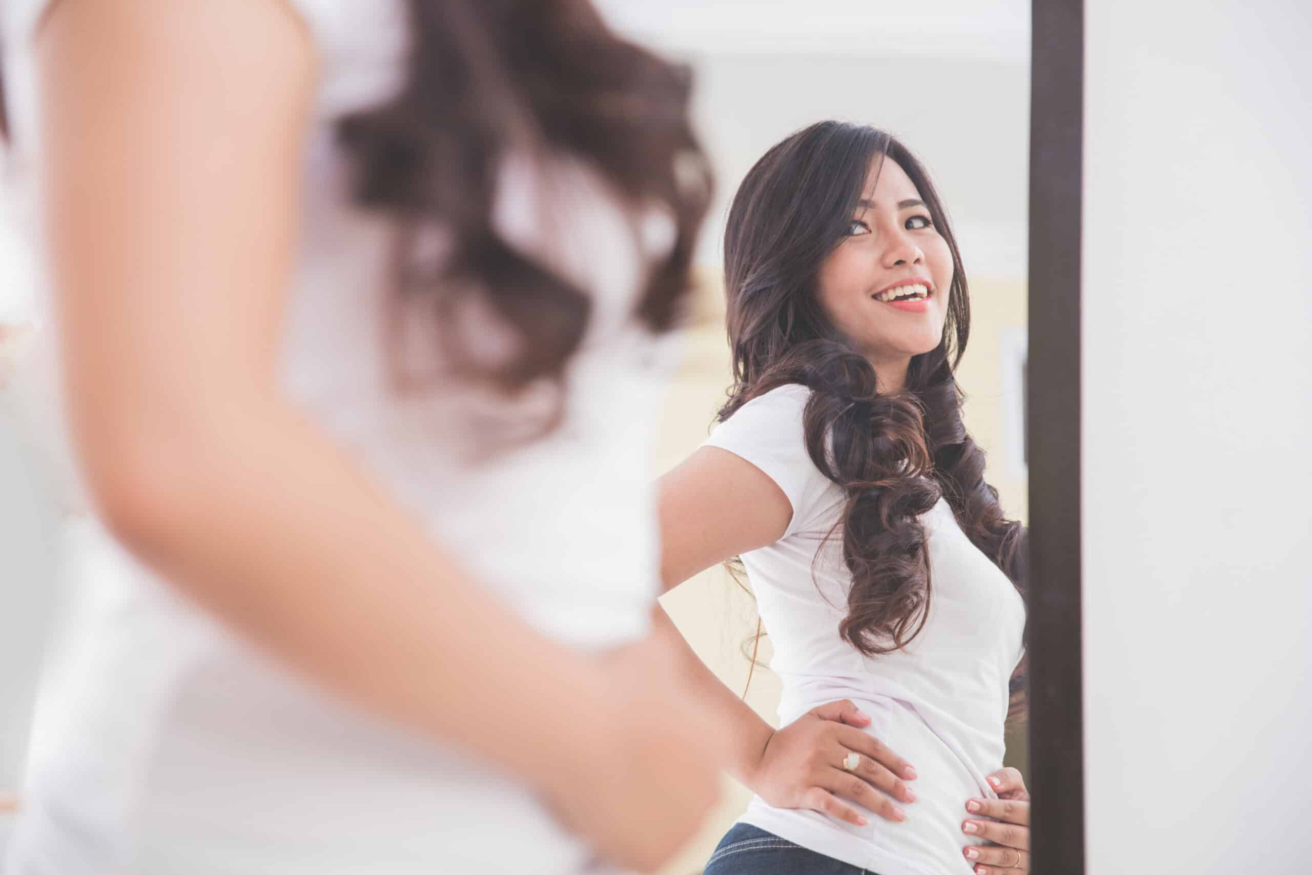 a young woman looking in the mirror at her stomach