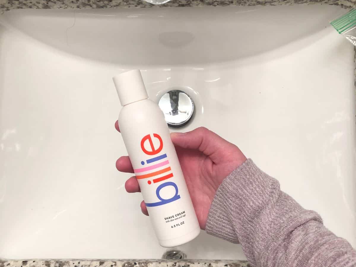 a hand holding a bottle of Billie shaving cream