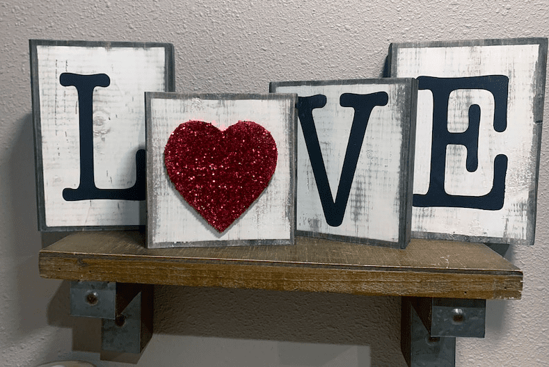 four wooden block letters that say L heart V and E