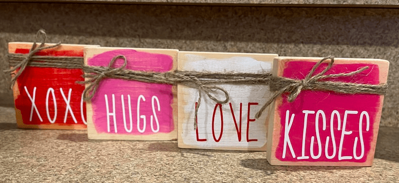 four wooden blocks painted and tied with rope that say xoxo hugs love kisses