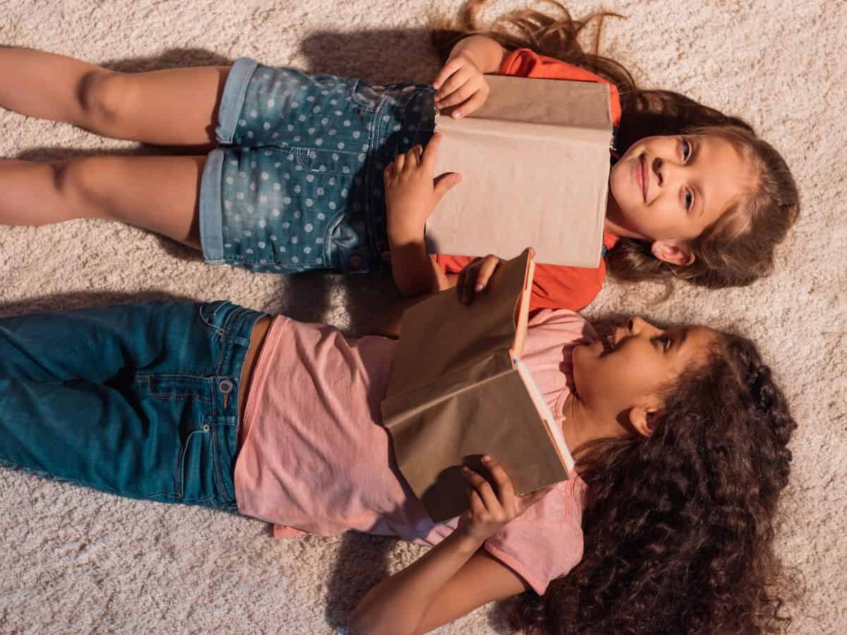 two girls reading books on the floor