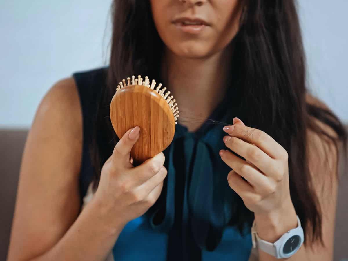 a woman with a hair brush noticing hair loss