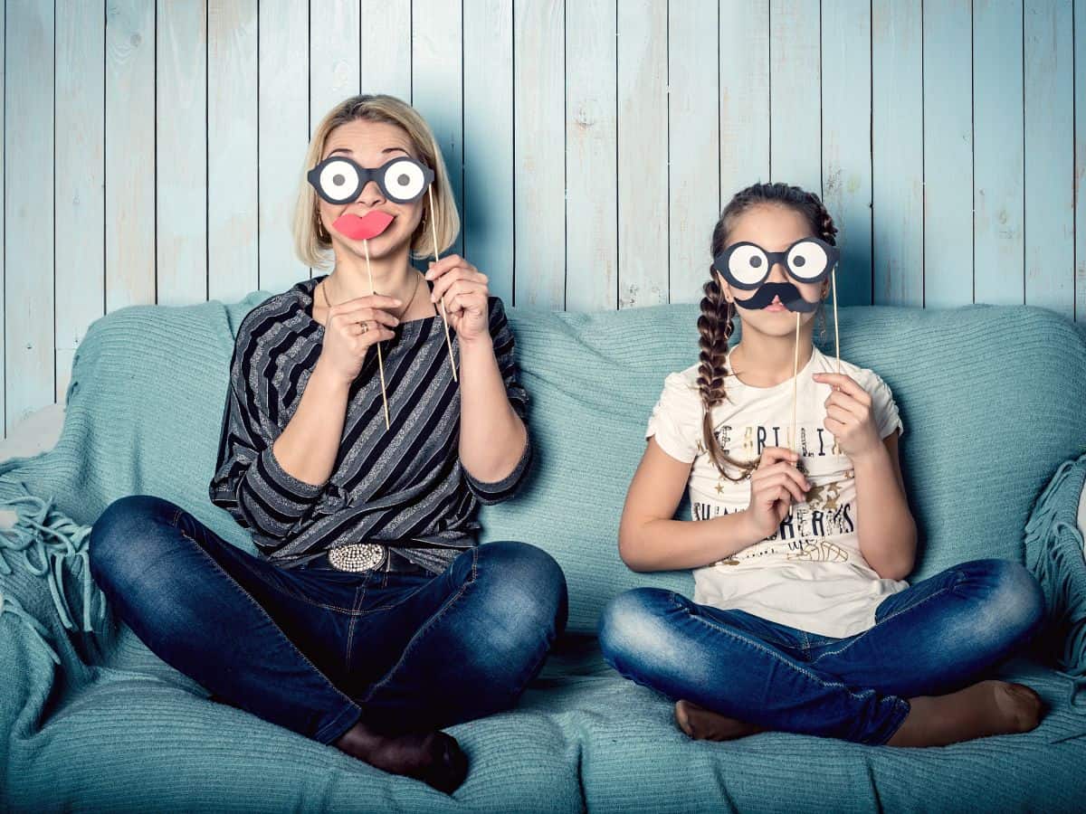 a mom and her daughter holding up pretend faces and being silly