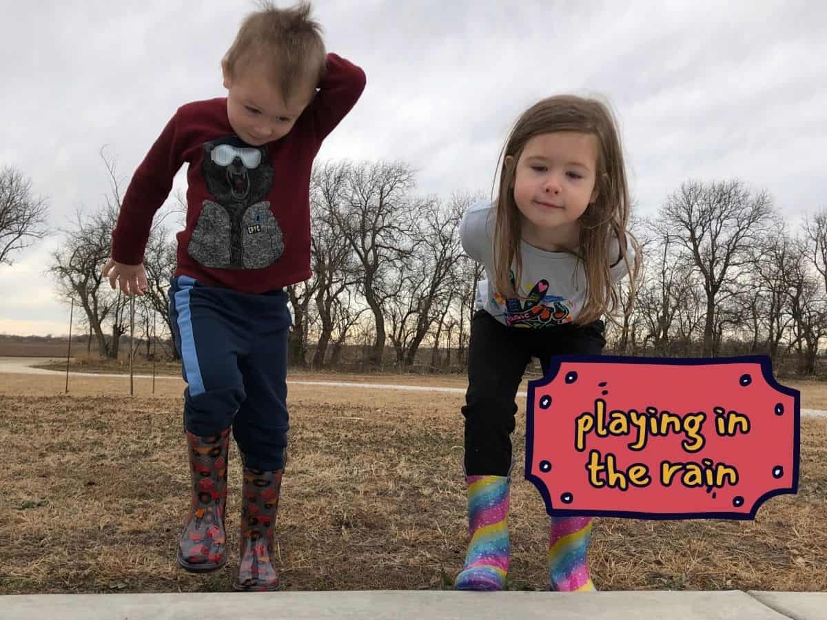 two kids with rain boots on a cloudy day with text overlay that reads playing in the rain