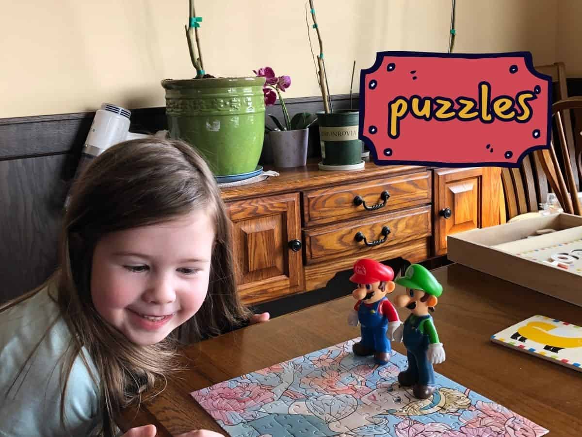 a little girl posing with her finished puzzle inside and text overlay that reads puzzles