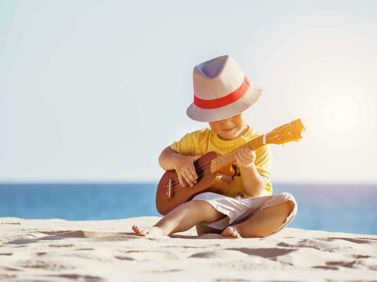 a young boy with a ukulele on the beach