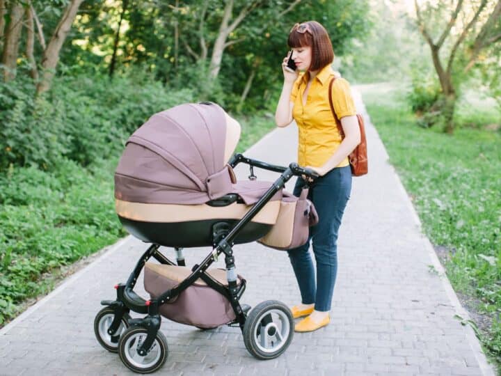 a young mom pushing a stroller in the park while on the phone