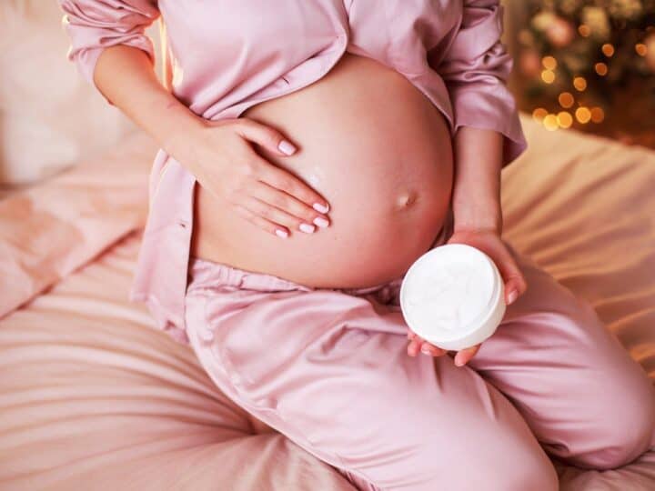 a pregnant woman rubbing cream on her belly