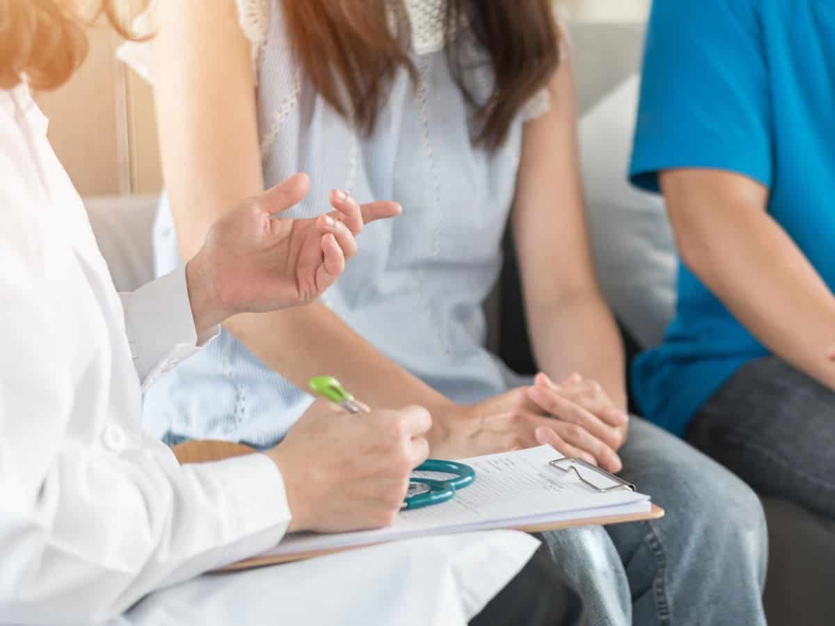 a wife and husband talking with a doctor