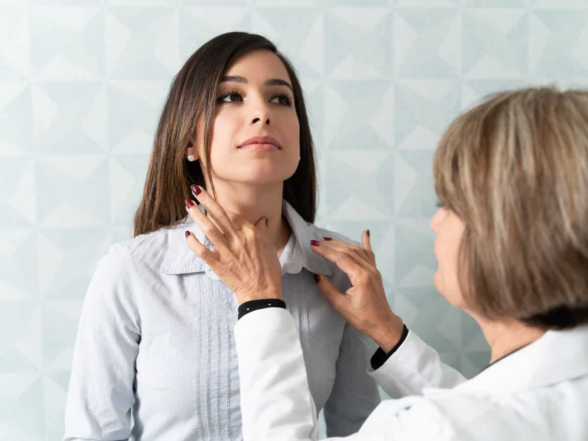 a doctor checking a woman's thyroid