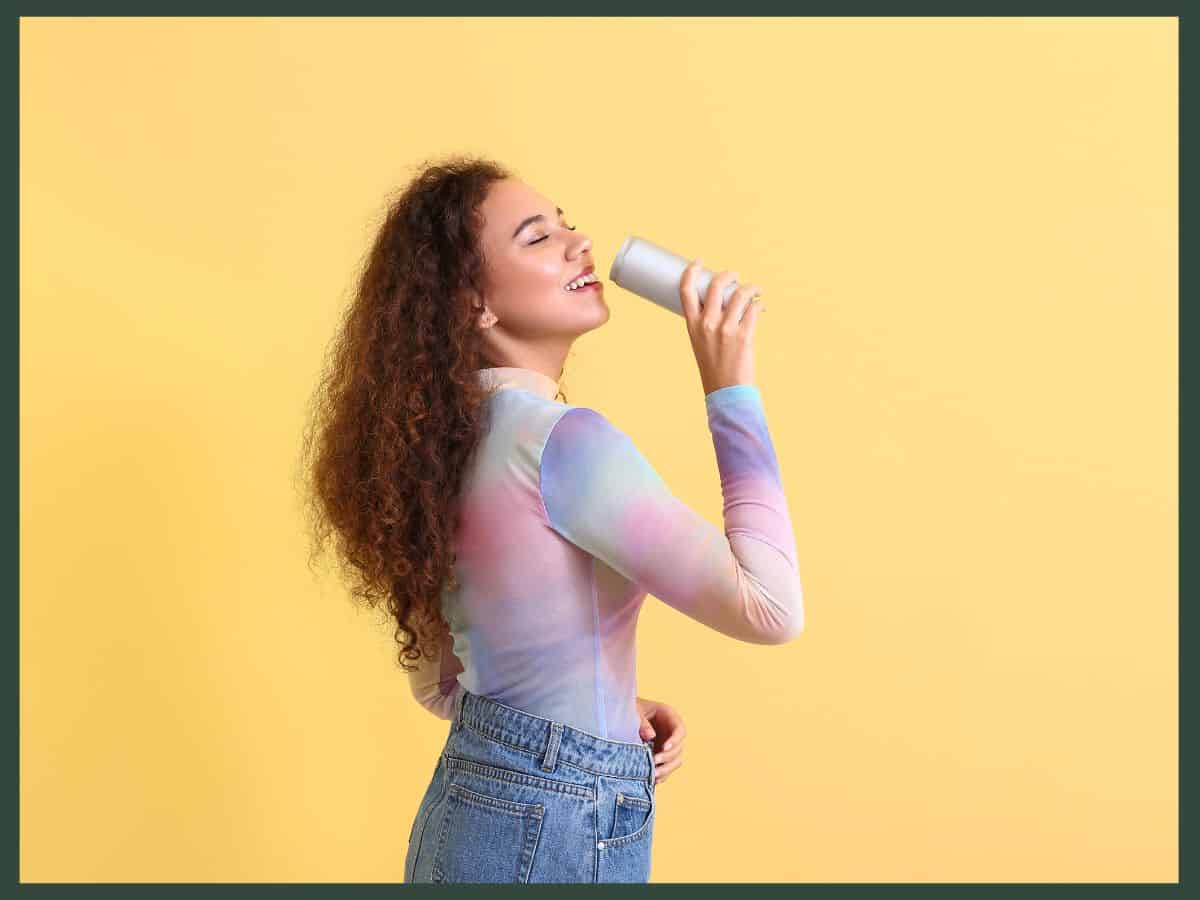 a woman drinking a can of gut health soda