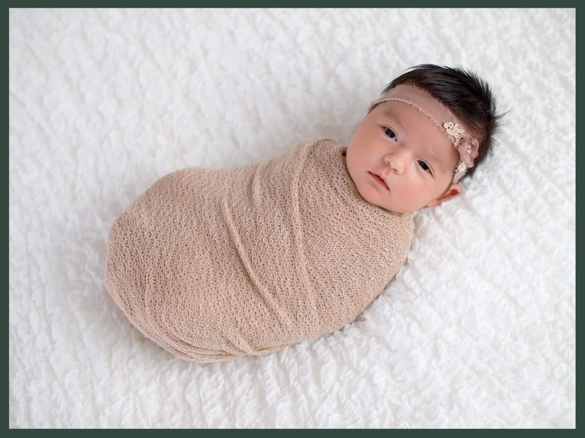 a baby girl swaddled in a muslin baby blanket