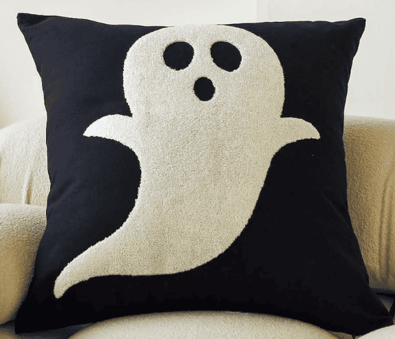 a black pillow with an embroidered ghost